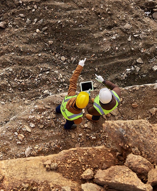Two people discussing while holding tablet at mining site